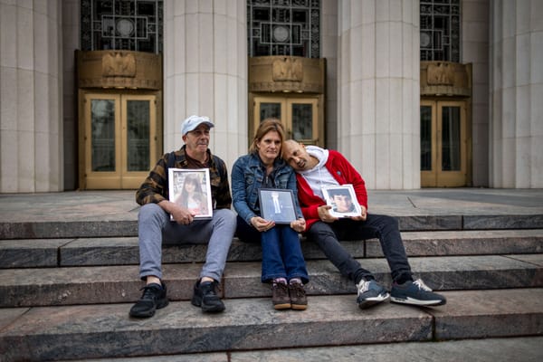 People hold photos of their children outside the Los Angeles Superior Court on February 11, 2026 in Los Angeles, California. 